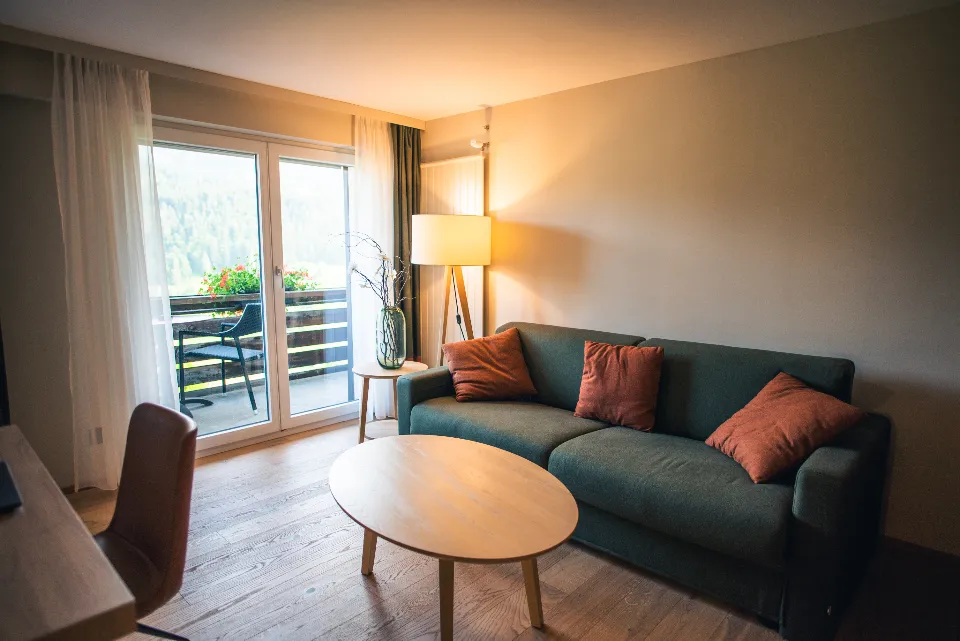 Ein gemütliches Wohnzimmer im warmen Abendlicht mit grünem Sofa und Stehlampe